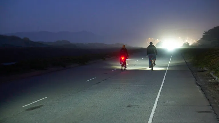 Kat and Connor riding away from the camera at Ocean Beach Park in the dark, with a bright light shining in front of them.