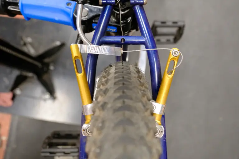 A view of the rear brake with a centimeter of space between the drooping cable guide and top of the tire.