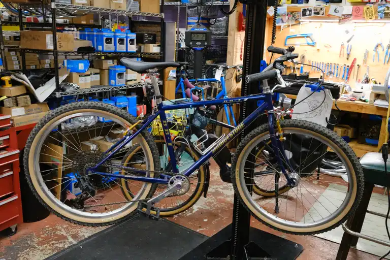 The bike hanging on a scale that reads 27lbs 2oz.