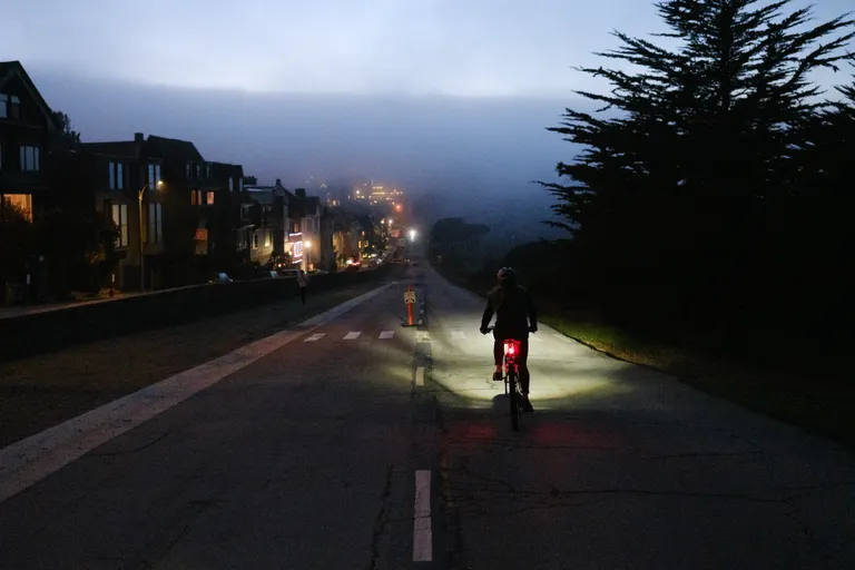 Kat riding down a hill at the edge of the Presidio with lots of fog.