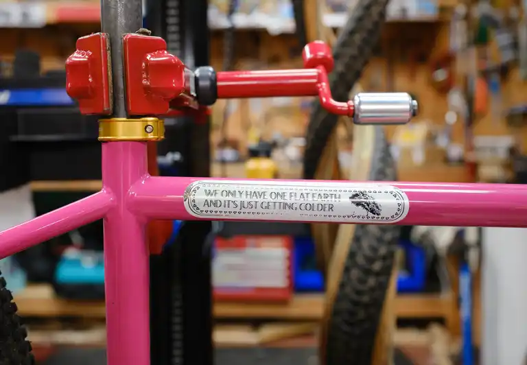 A sticker on the top tube of a pink bike that reads 'We only have one flat earth and it's just getting colder'
