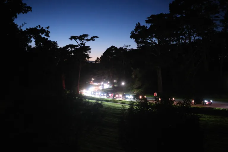 A dark view of the winding JFK road with cars lined up into the vanishing point