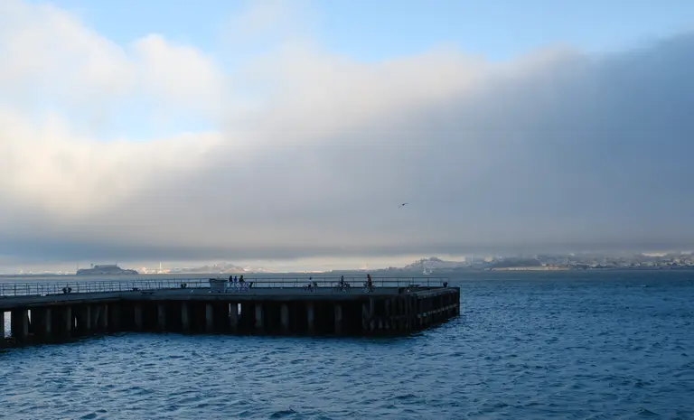 A dock with most of San Francisco in the background fogged over.