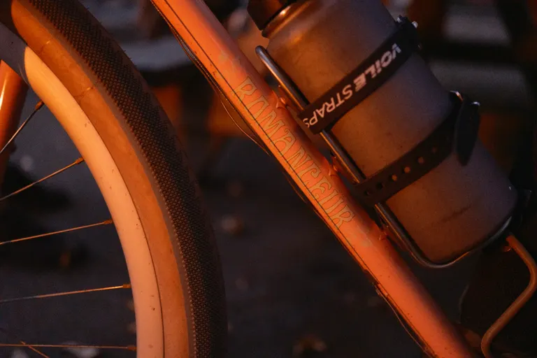 The Romanceur logo on the downtube of a bike in the glow of a campfire
