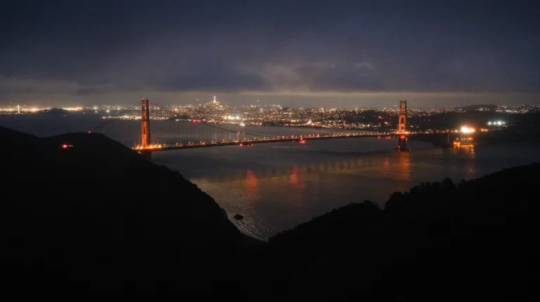 The Golden Gate Bridge and San Francisco skyline at night with a straight line of clouds just barely above it.