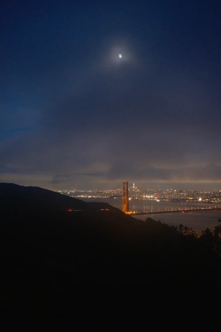 The moon over the Golden Gate Bridge and Salesforce tower.