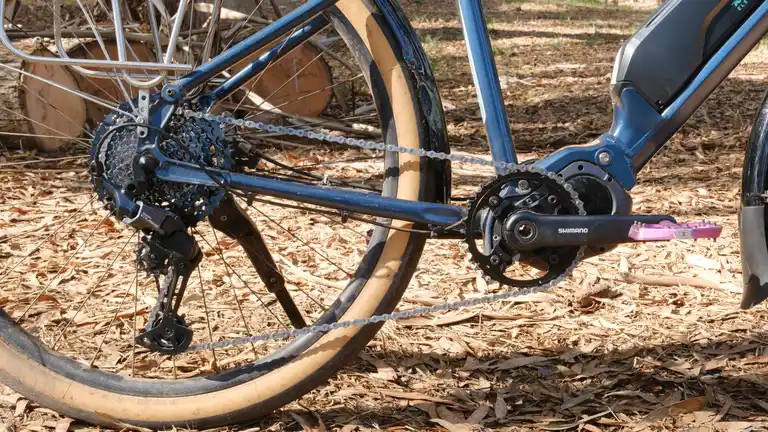 The drivetrain of a blue e-bike with a new Shimano CUES cassette, derailleur, and chainring.