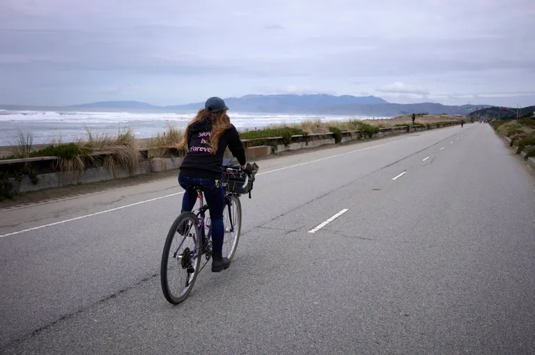 Kat biking in a black 'slow is forever' sweater on a windy day