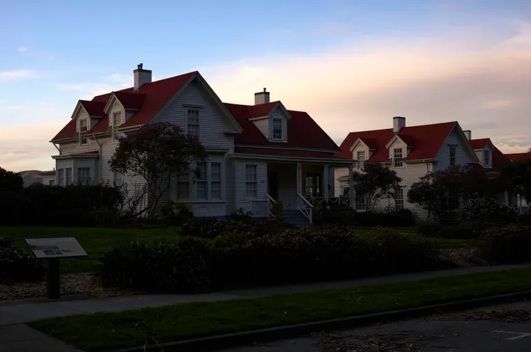 Two homes in front of lawns at sunset