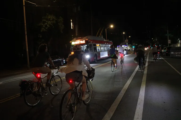 Several people riding bikes with Kat in the foreground backlit by a 33 trolley bus.