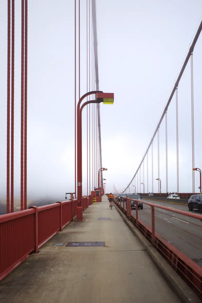 The west sidewalk of the Golden Gate Bridge with Ben riding into the foggy background