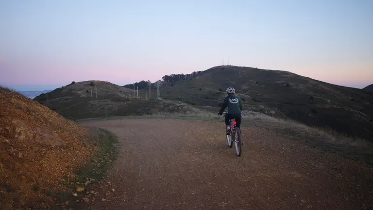 Kat in a green hoodie riding down Bobcat trail around sunset.