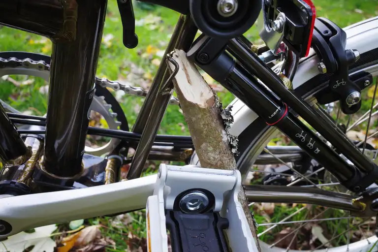 A stick wedged between the ground and a braze-on of the rear triangle of a Brompton.