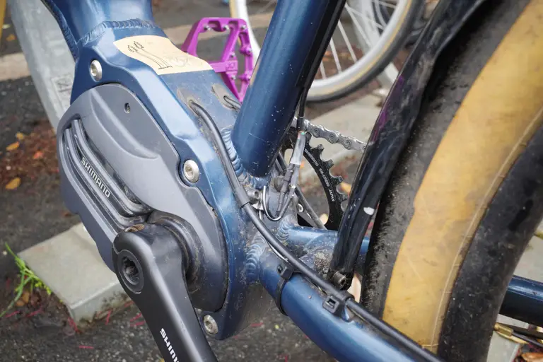 The seat tube/chainstays cluster of an e-bike showing the dynamo wire going through a fender strut clamp.